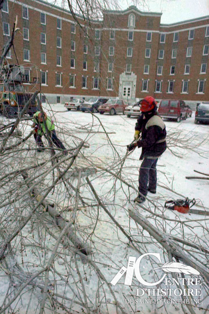 Il faut nettoyer les lieux. Ici, des travailleurs s'affairent à ramasser et à couper les branches qui jonchent le sol devant l'immeuble du 2200 Pratte.